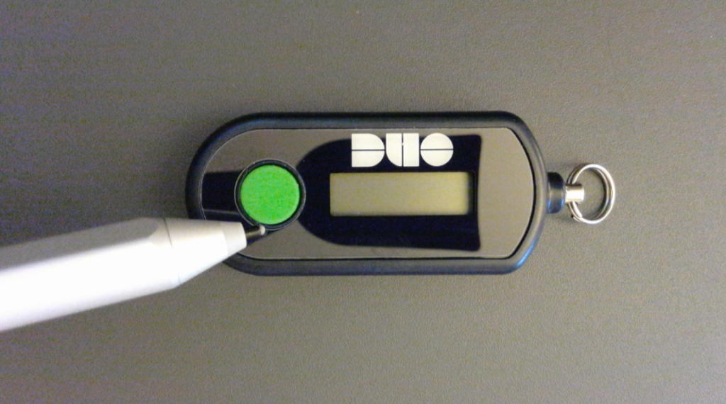 Pointer indicating the location of the green button on the bottom (or left) side of the device.